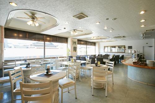 um restaurante com cadeiras e mesas brancas e um bar em Kanku Sun Plus Yutaka em Izumi-Sano