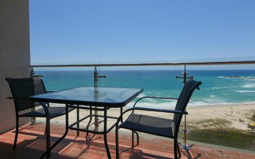 una mesa y sillas en un balcón con vistas a la playa en Princess Palm on the Beach, en Gold Coast