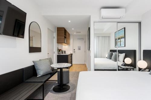 Quest Perth Ascot في بيرث: غرفة نوم مع سرير وغرفة معيشة