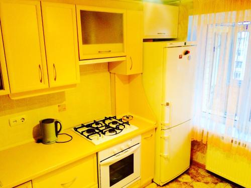 a yellow kitchen with a stove and a refrigerator at Apartment on Shevchenka Boulevard in Cherkasy