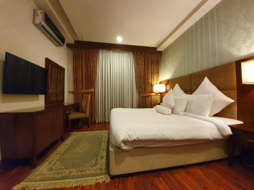 a hotel room with a bed and a flat screen tv at S Chalet Islamabad in Islamabad