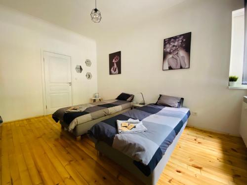 two beds in a room with wooden floors at Spacious modern vintage flat in the heart of Sofia in Sofia