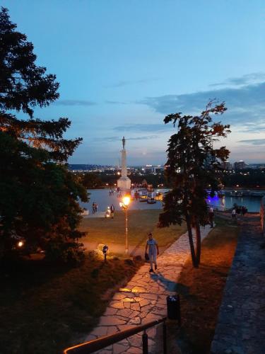 a man walking down a path with a lighthouse in the background at Apartments best city place in Belgrade