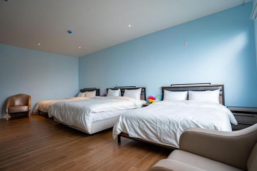 two beds in a room with blue walls and wooden floors at 芸彩莊園 in Renai