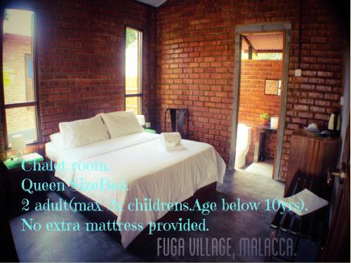 a bedroom with a white bed in a brick wall at Fuga Village BeachGetaway in Melaka