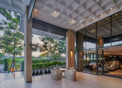 a lobby of a building with tables and chairs at The Park Nine Hotel Suvarnabhumi in Lat Krabang