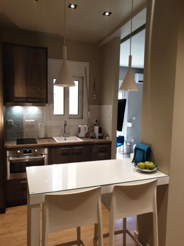 a kitchen with a white table and white chairs at Newly Renovated Studio 15 min walk from Acropolis in Athens