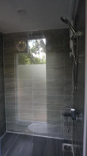 La salle de bains est pourvue d'une douche et d'une fenêtre. dans l'établissement Moon Garden Homestay - cozy cabin and natural pool in Tay Ninh, à Tây Ninh