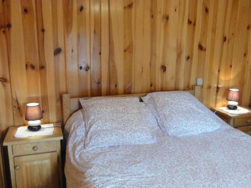 a bedroom with wooden walls and a bed with two lamps at Holiday cottage in Lozre in a pretty corner of Margeride in Mialanes