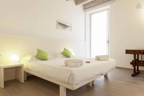 a white bedroom with a large bed with green pillows at Residenza Cardo Massimo in Verona