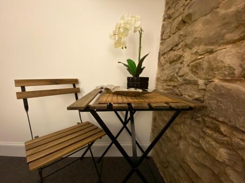 a table and a bench next to a stone wall at Royal Mile Balconies by the Castle in Edinburgh