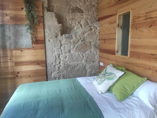 Bett in einem Zimmer mit einer Steinmauer in der Unterkunft Hospédate Pontevedra in Pontevedra