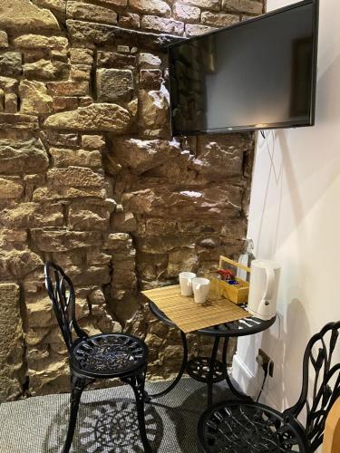a table and chairs in front of a stone wall at Royal Mile Balconies by the Castle in Edinburgh