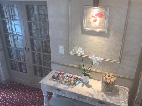 a table with a vase of flowers on it at Les 3 rois by YY in Villers-Bocage