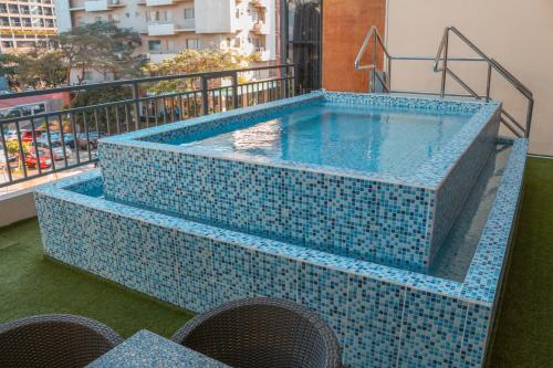マニラにあるThe B Hotel Alabangの青いタイルのバルコニー付きのスイミングプール