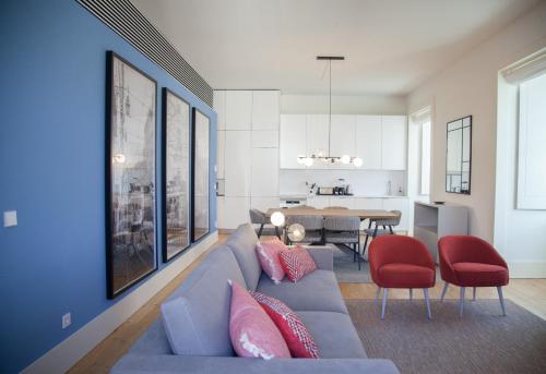 un soggiorno con divano blu e sedie rosse di FLH Augusta's Arch Design Apartment a Lisbona