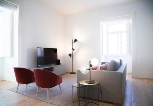ein Wohnzimmer mit einem weißen Sofa und roten Stühlen in der Unterkunft FLH Augusta's Arch Design Apartment in Lissabon