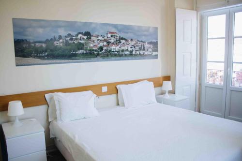 Un dormitorio con una cama blanca con una foto en la pared en Casa João Chagas Guesthouse, Constância, en Constância