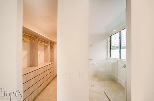 baño con paredes blancas y ducha a ras de suelo en Splendeur Sur La Mer - Three Bedroom, en Airlie Beach
