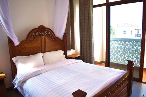 Schlafzimmer mit einem Bett mit einem Kopfteil aus Holz und einem Fenster in der Unterkunft Sultan Palace Beach Resort - AMANI Apartment CB2-202 in Kikambala
