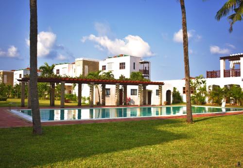 ein Swimmingpool vor einem Gebäude mit Palmen in der Unterkunft Sultan Palace Beach Resort - AMANI Apartment CB2-202 in Kikambala