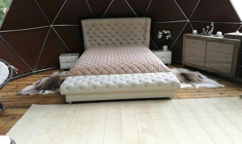 a bedroom with a bed with a white tufted bedskirts at kupolas in Šiauliai