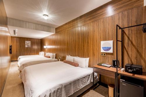two beds in a hotel room with wooden walls at Mayer Inn in Taipei