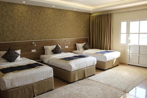 a hotel room with two beds and a window at Al Diyar Hotel in Nizwa