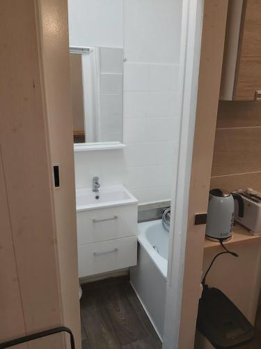 une salle de bain blanche avec un lavabo et un miroir dans l'établissement STUDIO RUE GAUTHEY PARIS 17, à Paris