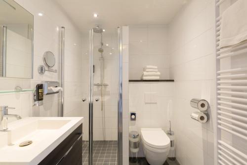 a bathroom with a toilet and a sink and a shower at Strandhotel Bos en Duin in Oostkapelle