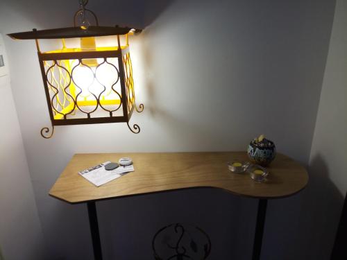 a table with a light and a lamp on a wall at Idria B&B in Barcellona-Pozzo di Gotto