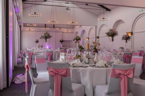 a room with white tables and chairs with pink bows at nestor Hotel Stuttgart-Ludwigsburg in Ludwigsburg