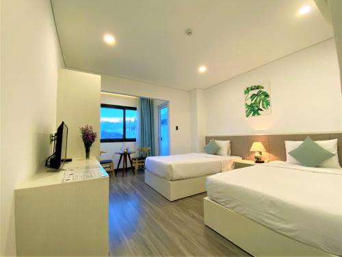 um quarto de hotel com duas camas e uma televisão em Olivia Hotel and Apartment em Nha Trang
