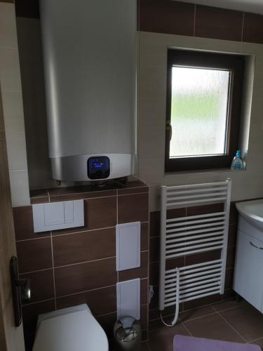 a bathroom with a toilet and a tv on the wall at Chata Seeberg in Poustka