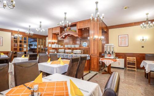 a restaurant with tables and chairs and chandeliers at Hotel Erzsébet in Hévíz
