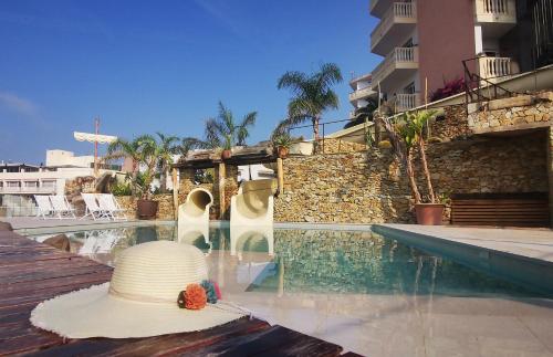 a hat sitting on a table next to a swimming pool at Hotel Alba Seleqtta in Lloret de Mar