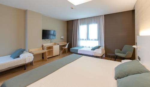 a hotel room with two beds and a television at Hotel Olympia Valencia in Alboraya