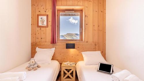 a room with two beds with a teddy bear sitting between them at Madame Vacances Residence Les Fermes de Saint Sorlin in Saint-Sorlin-dʼArves