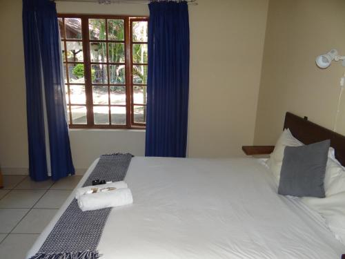 a bedroom with a large white bed with a window at Lepha Guest House in Onverwacht