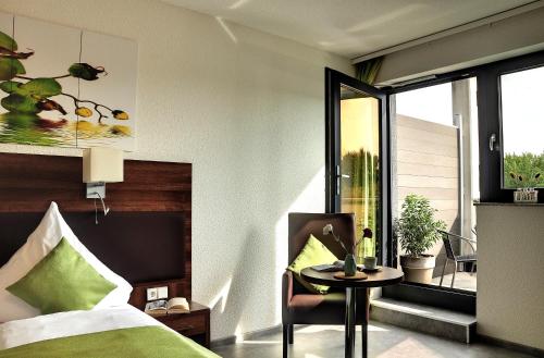 a bedroom with a bed and a table and a window at Motel am Fürfelder Schloss in Bad Rappenau