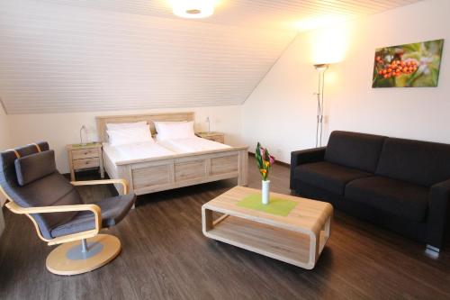 Zimmer mit einem Bett, einem Sofa und einem Stuhl in der Unterkunft Gästehaus Meng in Bad Krozingen