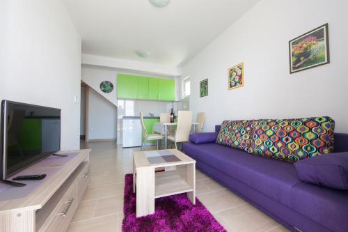 a living room with a purple couch and a tv at Apartments Nevenka i Josko in Tučepi