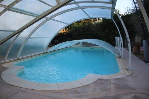 een groot zwembad onder een boog in een achtertuin bij Philippe & Marie, A louer Petite Chambre chez l'habitant avec terrasse dans Villa, au pied du Luberon in Cucuron