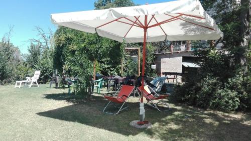 um guarda-chuva branco e algumas cadeiras e uma mesa em Agriturismo La Chiesina em Abbadia di Montepulciano