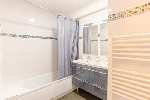 La salle de bains est pourvue d'un lavabo, d'une baignoire et d'un miroir. dans l'établissement Lorient HYPERCENTRE-LUMINEUX-TOUT CONFORT-BALCON, à Lorient