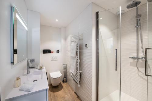 a white bathroom with a shower and a toilet at Résidences Alticimes in Brides-les-Bains