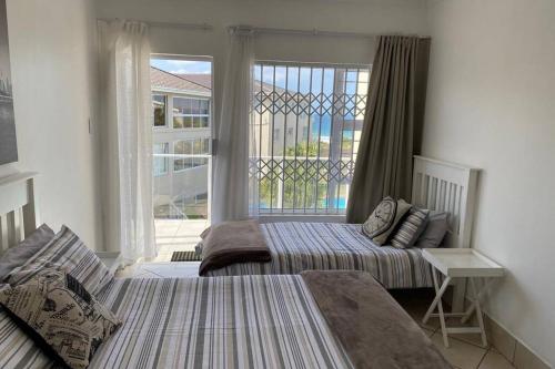 a bedroom with two beds and a large window at Uvongo Chalets 12 in Margate