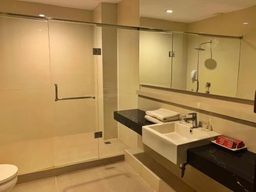 a bathroom with a sink and a shower and a toilet at Ameera Hotel in Pekanbaru