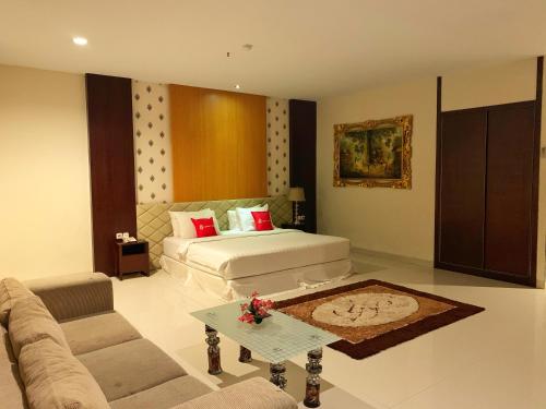een woonkamer met een bed en een bank bij Ameera Hotel in Pekanbaru