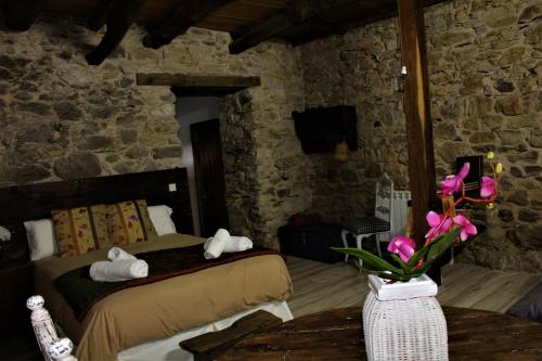 1 dormitorio con 1 cama y 1 mesa con flores en Alojamientos Serra da Lastra, en Villar de Silva